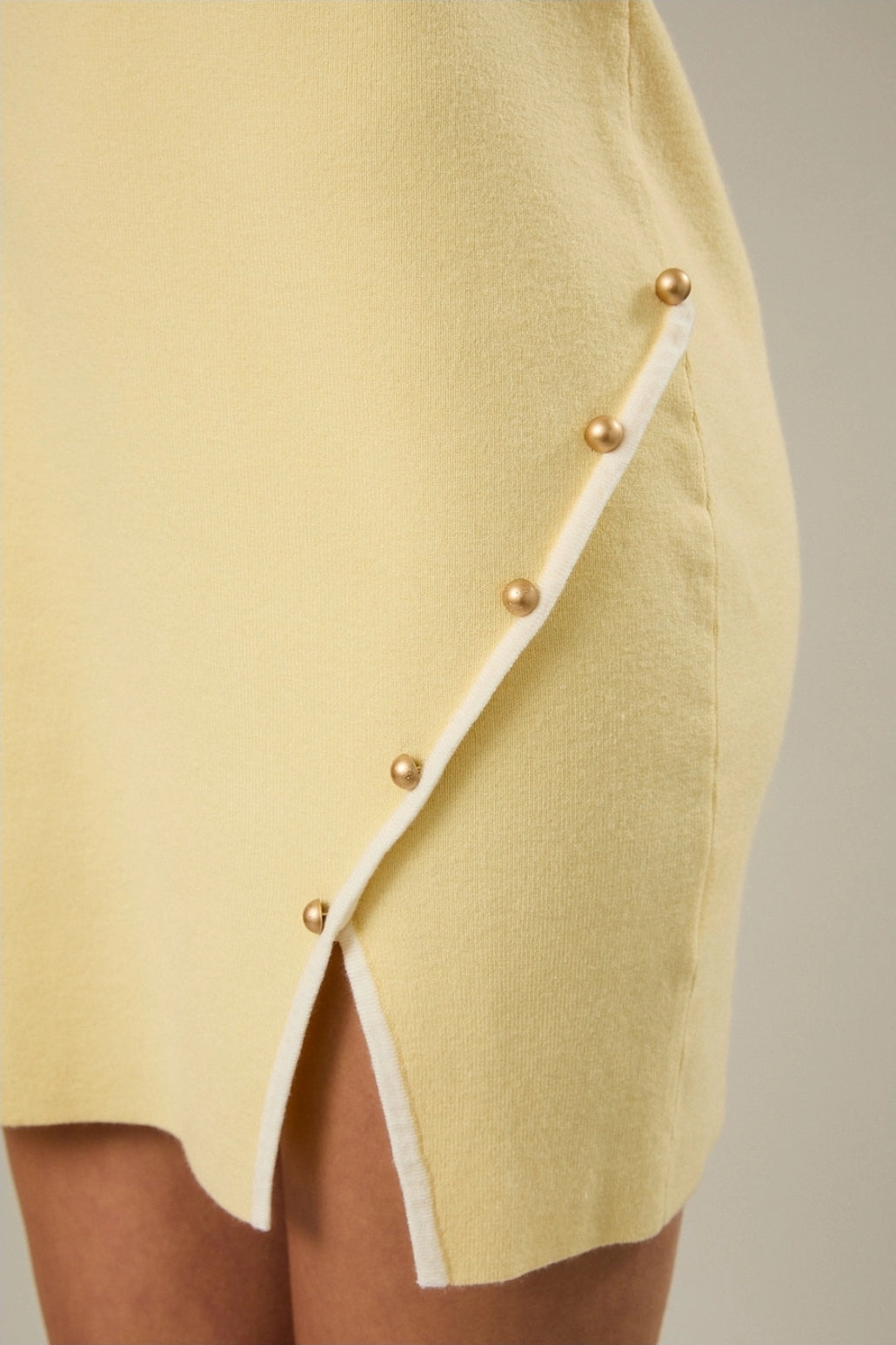 A sleek sleeveless mini dress in pale yellow with a chic side button slit. Light image 3